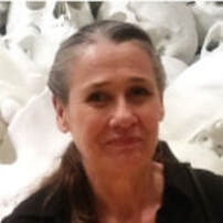 Headshot of Vicki Borthwick smiling in front of a pile of skulls.